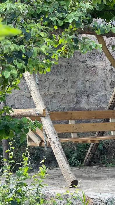 Wooden swing bench beside a stone wall