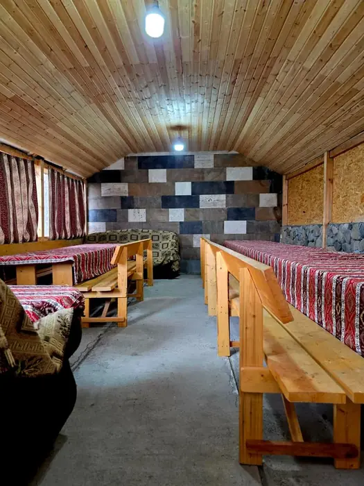 Covered hall with two long tables laid in red Armenian carpet cloth