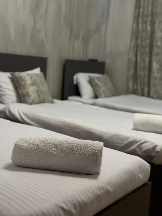 Beds made up with striped linen and a towel rolled on each